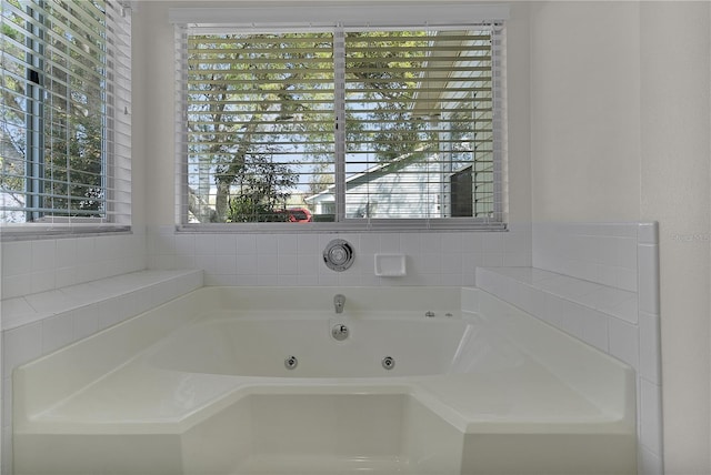 bathroom with a healthy amount of sunlight and a tub with jets