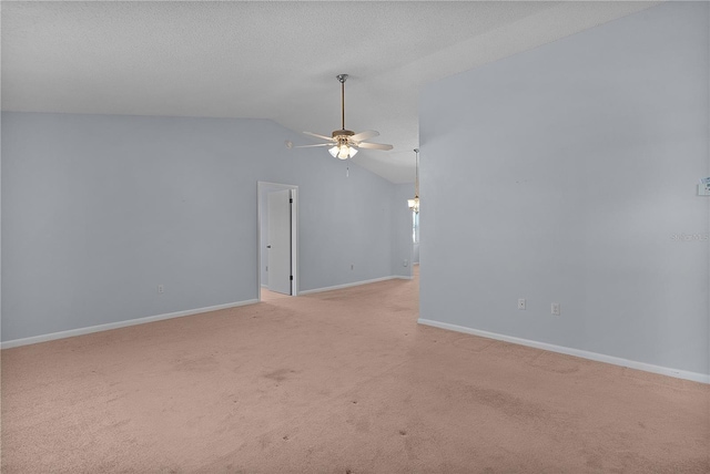 spare room featuring light carpet, lofted ceiling, a ceiling fan, a textured ceiling, and baseboards