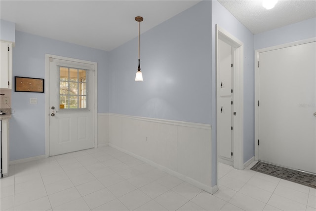 entrance foyer featuring light tile patterned floors and wainscoting