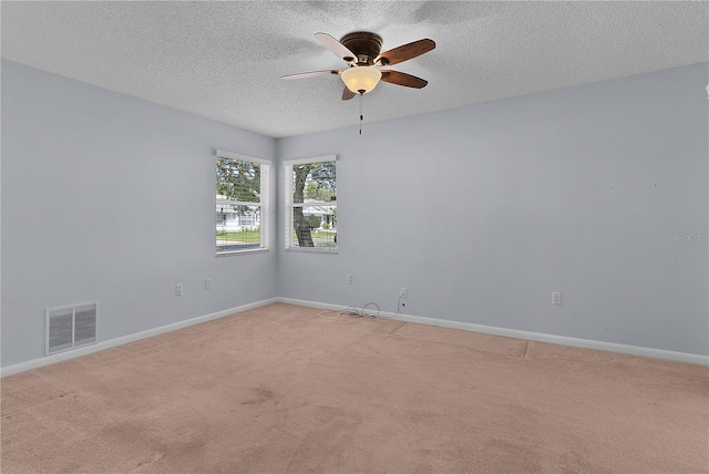 empty room with visible vents, baseboards, light carpet, a textured ceiling, and a ceiling fan