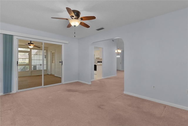 spare room featuring light colored carpet, arched walkways, visible vents, and ceiling fan