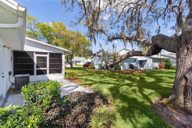 view of yard featuring a sunroom and central AC