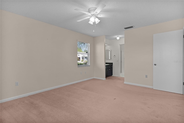 unfurnished living room with visible vents, light carpet, a ceiling fan, a textured ceiling, and baseboards