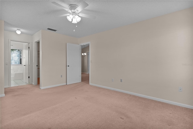 unfurnished bedroom featuring baseboards, visible vents, ensuite bath, a textured ceiling, and light carpet