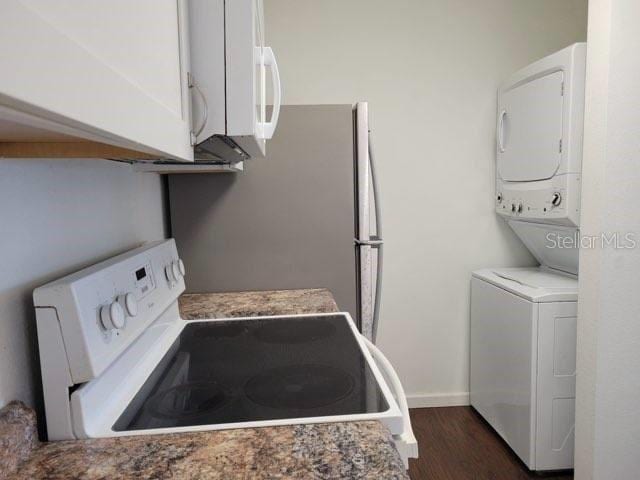 clothes washing area with stacked washer and dryer, dark wood-type flooring, laundry area, and baseboards