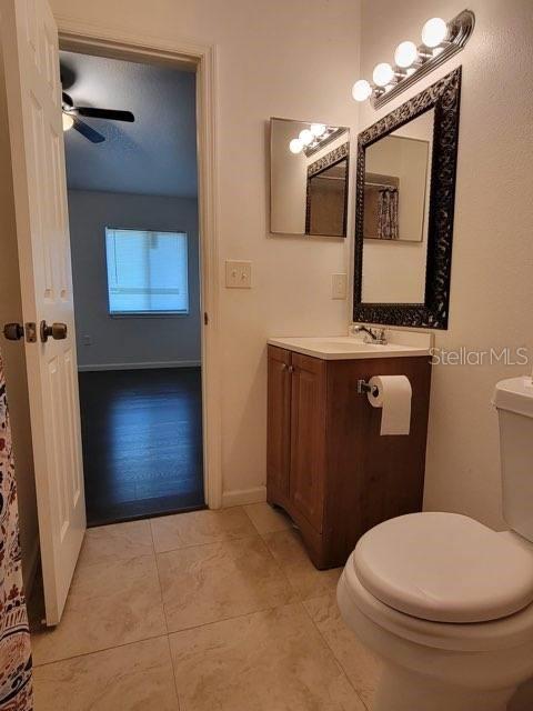 bathroom with toilet, tile patterned flooring, baseboards, and vanity