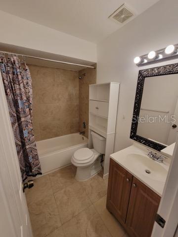 bathroom with toilet, vanity, visible vents, and shower / tub combo with curtain