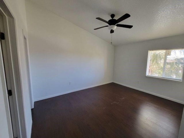 spare room featuring ceiling fan, a textured ceiling, baseboards, vaulted ceiling, and dark wood finished floors