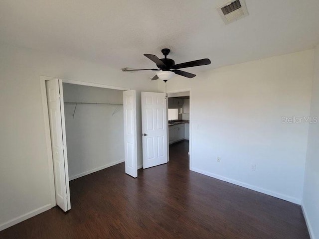 unfurnished bedroom featuring baseboards, a closet, visible vents, and wood finished floors