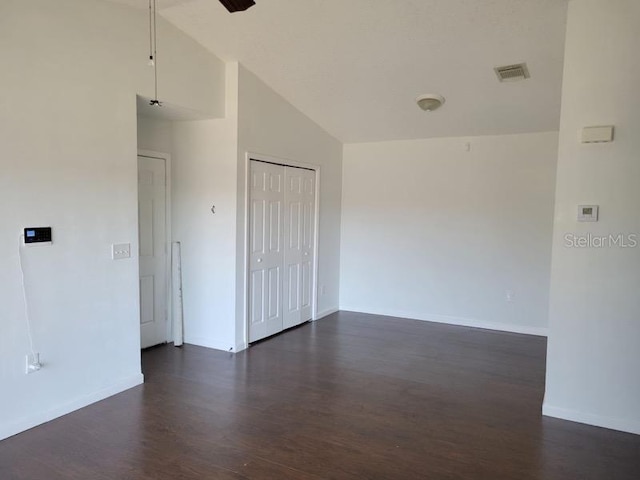 empty room with high vaulted ceiling, baseboards, visible vents, and dark wood-type flooring