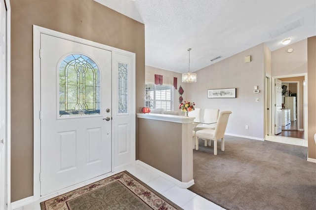 carpeted foyer with lofted ceiling, visible vents, an inviting chandelier, a textured ceiling, and baseboards