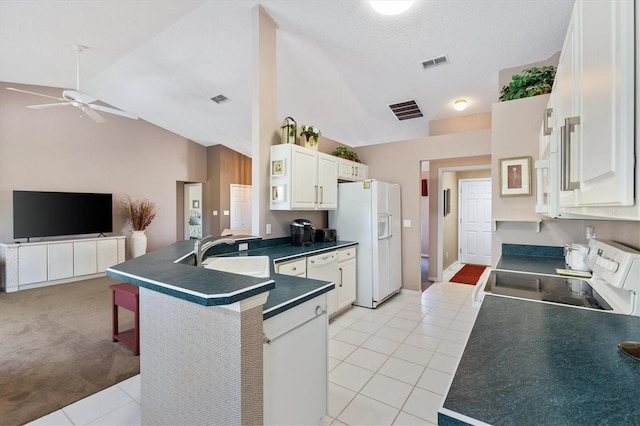 kitchen featuring dark countertops, visible vents, open floor plan, a sink, and white appliances