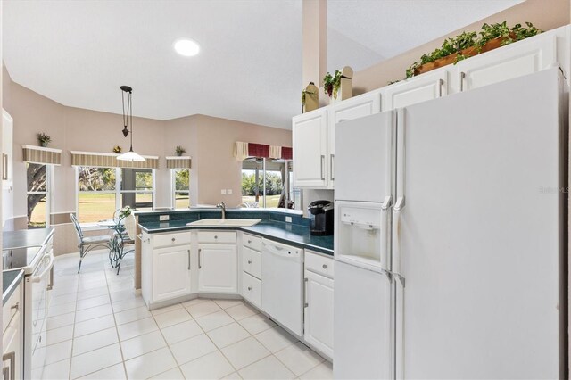 kitchen featuring white appliances, white cabinets, a sink, and a peninsula