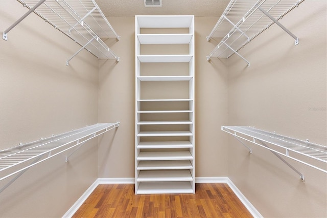 walk in closet with visible vents and wood finished floors