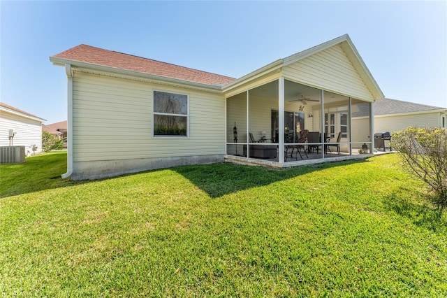 rear view of house with a ceiling fan, a sunroom, and a lawn