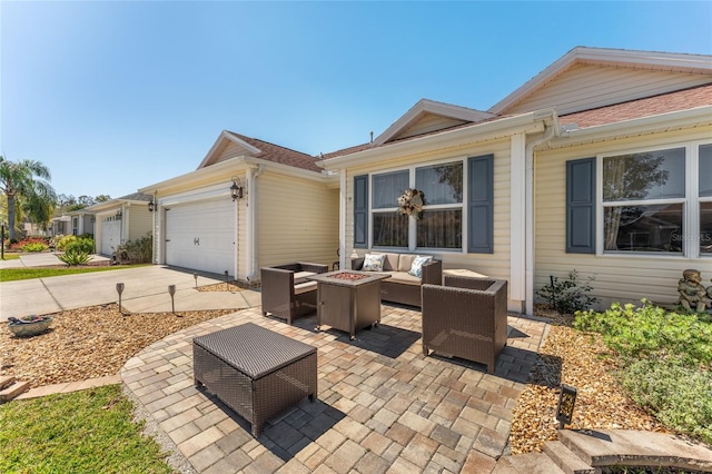 exterior space with concrete driveway, an attached garage, and an outdoor living space with a fire pit