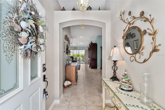 foyer entrance with arched walkways, baseboards, and light tile patterned floors