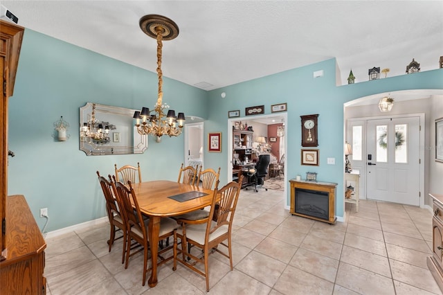 dining space with an inviting chandelier, light tile patterned floors, and baseboards