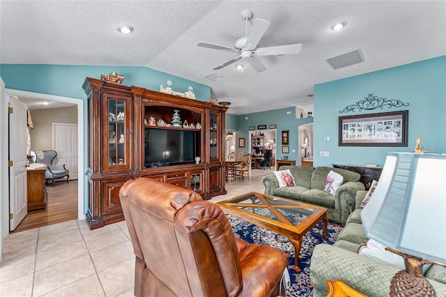 living room with light tile patterned floors, visible vents, a ceiling fan, lofted ceiling, and a textured ceiling