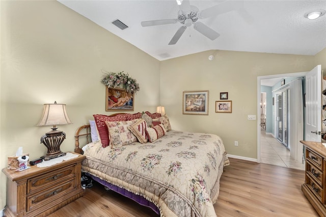 bedroom with baseboards, visible vents, a ceiling fan, vaulted ceiling, and light wood-style floors