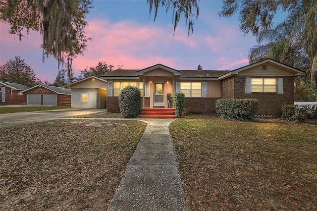 view of front facade featuring concrete driveway, brick siding, a front yard, and an outdoor structure