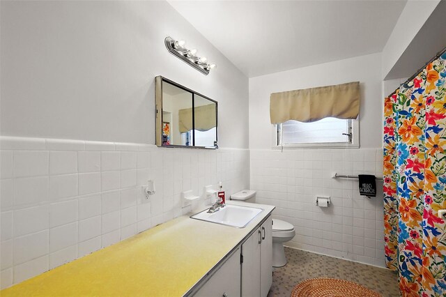 full bathroom with a shower with shower curtain, toilet, a wainscoted wall, vanity, and tile walls