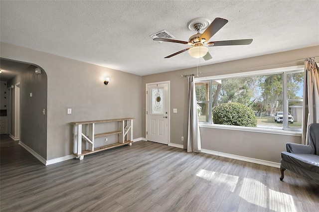 foyer entrance featuring a wealth of natural light, visible vents, arched walkways, and wood finished floors