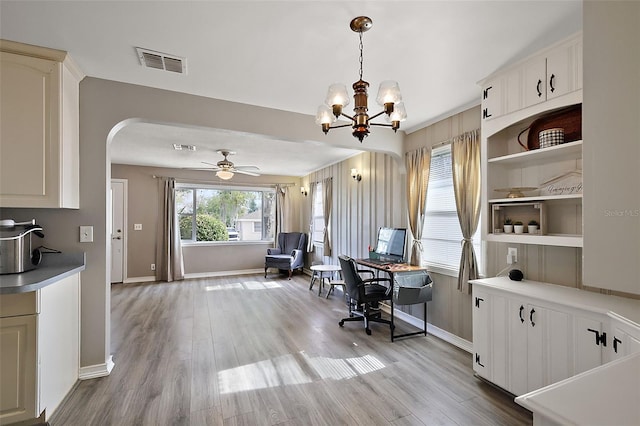 office featuring baseboards, visible vents, arched walkways, wood finished floors, and ceiling fan with notable chandelier