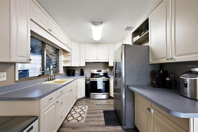 kitchen with appliances with stainless steel finishes, a sink, under cabinet range hood, and open shelves