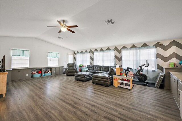 living area featuring dark wood-style floors, lofted ceiling, a healthy amount of sunlight, and visible vents