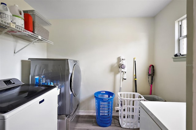 clothes washing area with laundry area, baseboards, washer and clothes dryer, and dark wood-style flooring