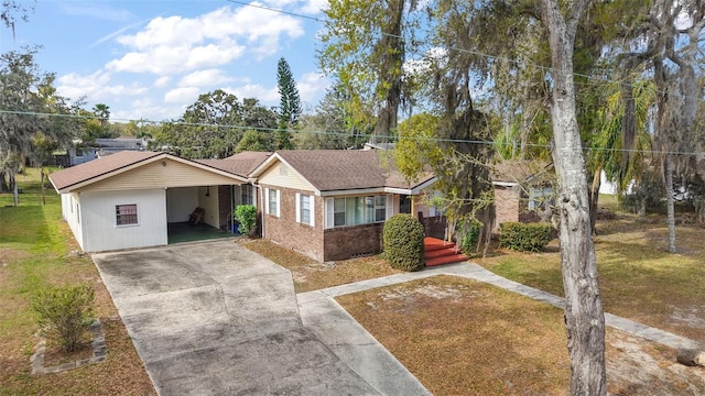 ranch-style home featuring a shingled roof, concrete driveway, brick siding, and a front lawn