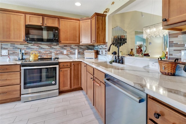 kitchen with a sink, light stone counters, stainless steel appliances, brown cabinetry, and decorative backsplash