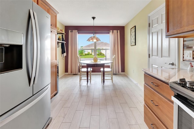 kitchen with brown cabinets, light wood finished floors, appliances with stainless steel finishes, light countertops, and hanging light fixtures