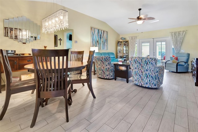 dining space with ceiling fan with notable chandelier, french doors, lofted ceiling, and wood tiled floor