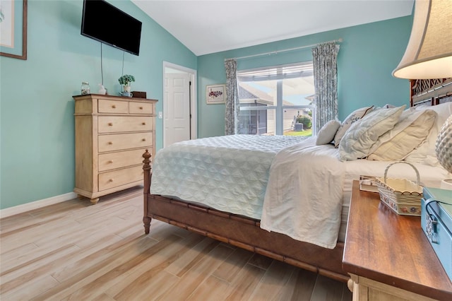 bedroom featuring baseboards, light wood-type flooring, and lofted ceiling