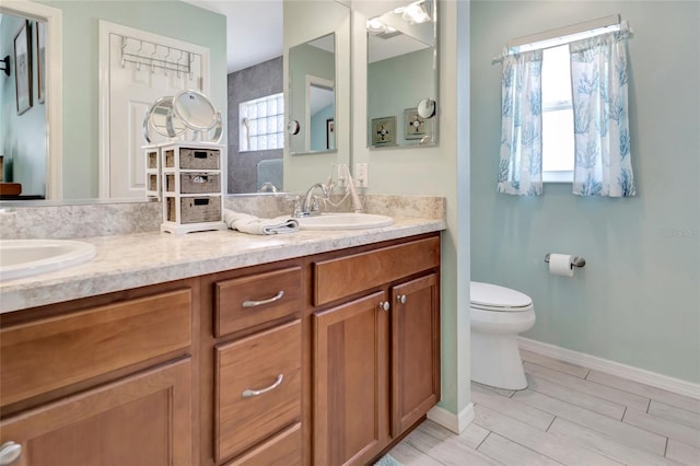 bathroom with walk in shower, double vanity, toilet, and a sink