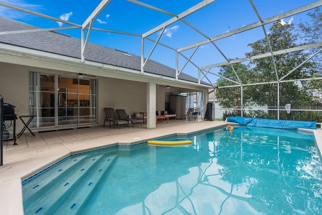 view of swimming pool featuring a patio area, a fenced in pool, glass enclosure, and a ceiling fan