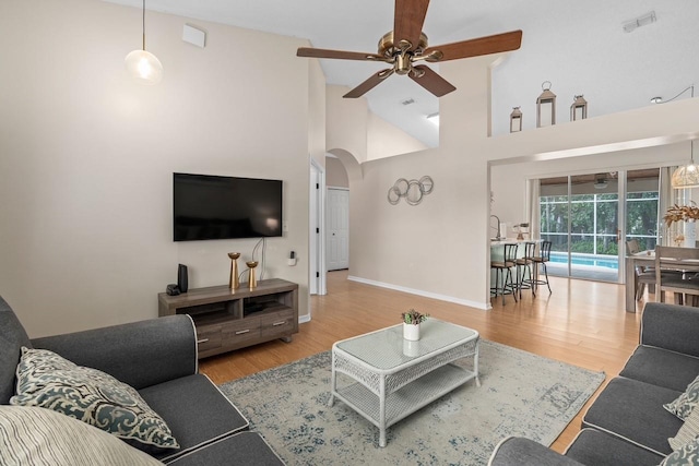 living area featuring arched walkways, visible vents, ceiling fan, and wood finished floors