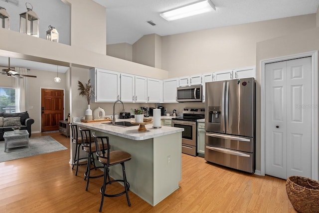 kitchen featuring light countertops, appliances with stainless steel finishes, a sink, a peninsula, and a kitchen breakfast bar