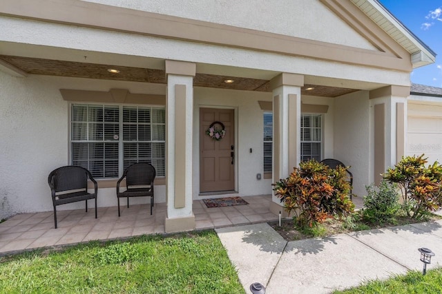 entrance to property featuring covered porch and stucco siding