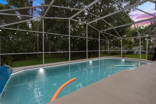 pool at dusk with glass enclosure, a yard, and a fenced in pool