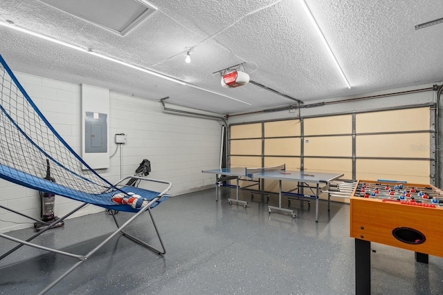 playroom featuring concrete block wall, a garage, electric panel, a textured ceiling, and speckled floor