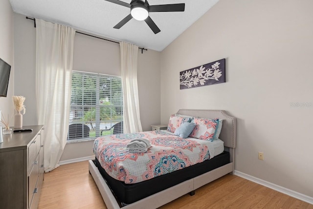 bedroom featuring lofted ceiling, light wood finished floors, baseboards, and a ceiling fan