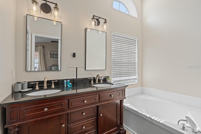 bathroom featuring double vanity, a garden tub, and a sink