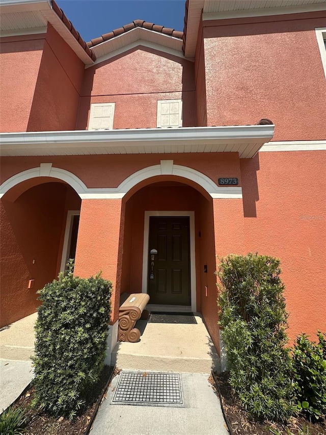 entrance to property with a tile roof and stucco siding