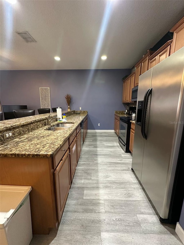 kitchen with visible vents, dark stone countertops, a peninsula, stainless steel appliances, and a sink