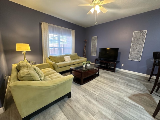 living room with ceiling fan, light wood-style flooring, and baseboards