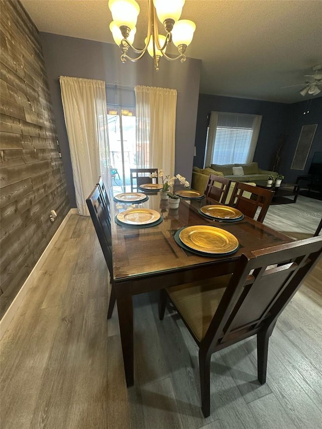 dining space featuring a textured ceiling, ceiling fan with notable chandelier, and wood finished floors