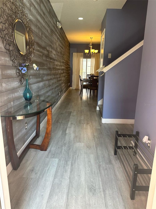 corridor with a chandelier, baseboards, and wood finished floors